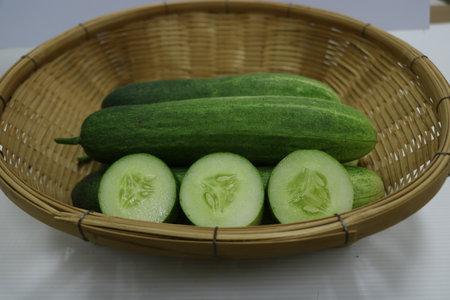 Cucumber in a wicker basket on a white background.の写真素材