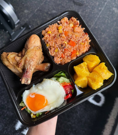 Fried rice with chicken, fried egg and vegetables in lunch boxの写真素材