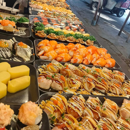 Variety of sushi and rolls on display at a Japanese street food marketの写真素材