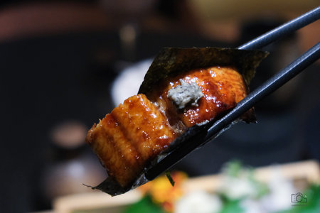 Grilled eel on chopsticks in a restaurant, Japanese foodの写真素材