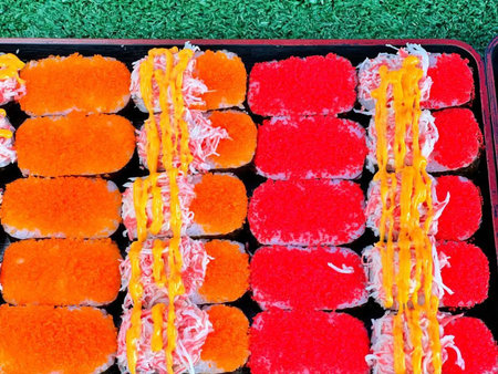 Sushi rolls in plastic box on green grass background, top viewの写真素材