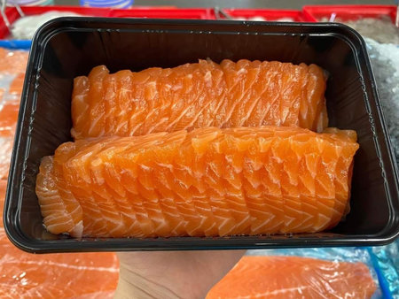 Salmon fillets in plastic box on ice for sale at market
