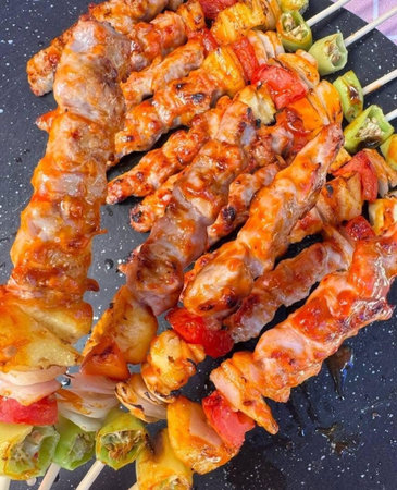 Skewers of pork with vegetables on a black plate.の写真素材