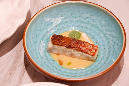 Fish fillet with mashed potatoes in a blue plate on a white background