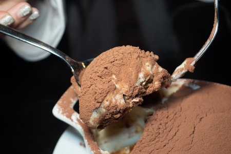 Chocolate ice cream with spoon on black background, selective focus.