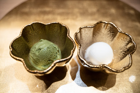 Green tea ice cream scoops in vintage bowl on wooden table.