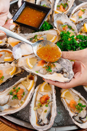 Oysters with oyster sauce and lemon on a wooden tableの写真素材