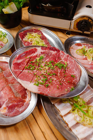 raw beef on a metal plate with vegetables and grinder on the backgroundの写真素材