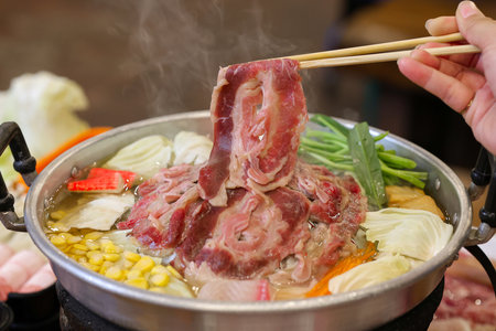 Pork belly being cooked in a pot with vegetables and chopsticksの写真素材