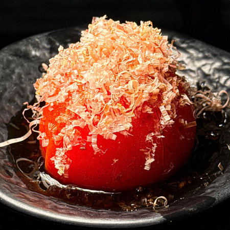Close up of a red tomato with shavings on a plateの写真素材