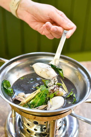Chef cooking oyster mushroom soup in hot pot at restaurant kitchenの写真素材