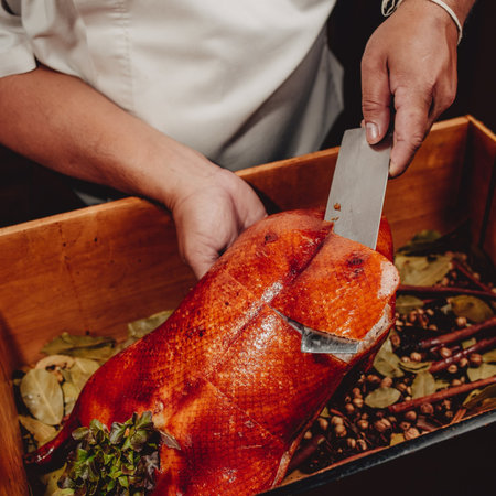chef cutting a roast duck with a knife in a restaurant kitchenの写真素材