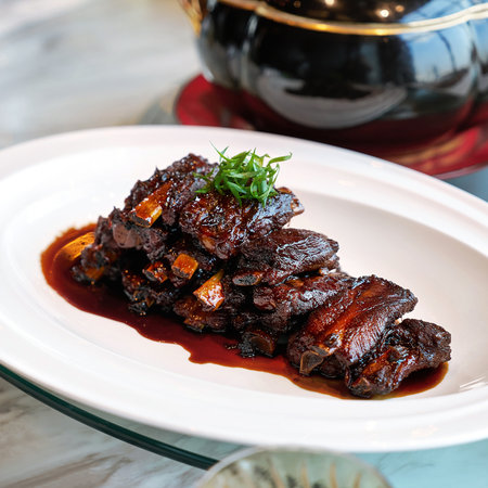 Braised pork ribs in teriyaki sauce on white plate.の写真素材