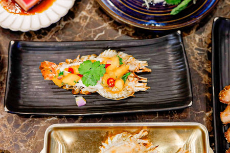 Grilled prawns with spicy sauce served on black plate.