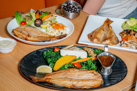 salmon fish with vegetables on a black plate on a wooden tableの写真素材