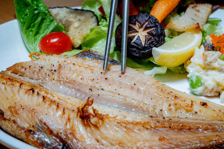 Grilled mackerel fillet with vegetables on a white plateの写真素材