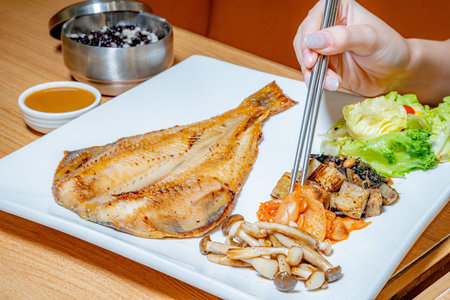 Grilled fish with vegetables on a white plate in a restaurant.