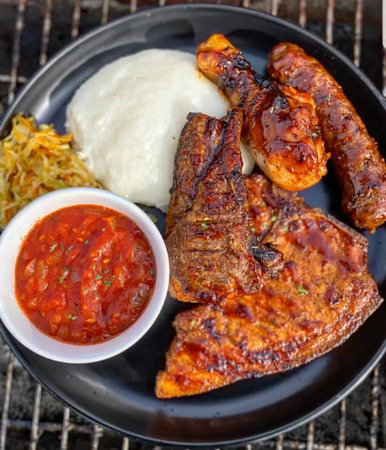 Grilled pork ribs with rice and ketchup on black plate.の写真素材