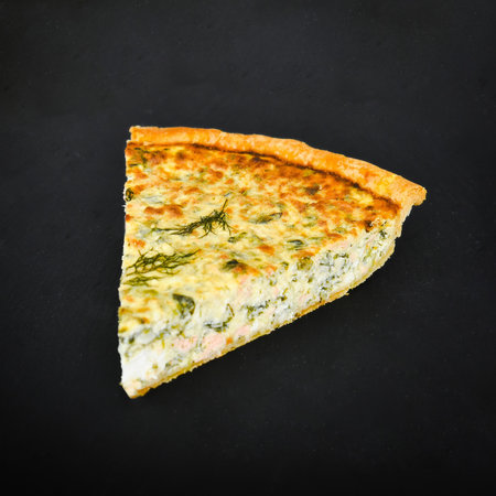 Quiche with spinach and cheese on a black background. Toned.の写真素材