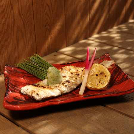Grilled fish with lemon on a red plate on a wooden table