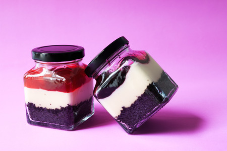 Two jars with creamy dessert: brownie base and yogurt topped with blueberries and Strawberryの写真素材