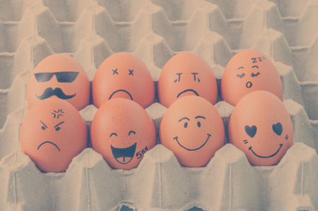 eight brown eggs  with faces drawn  arranged in cartonの写真素材