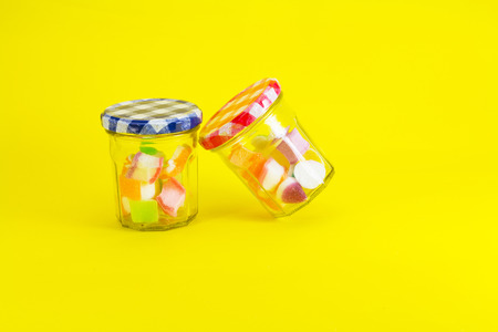 Colorful jelly candies in jar on yellow backgroundの写真素材