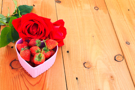 Red Strawberry in pink heart shape bowl with red roseの写真素材