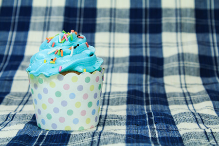 Blue Cupcake with colorful candy on blue picnic tableclothの写真素材