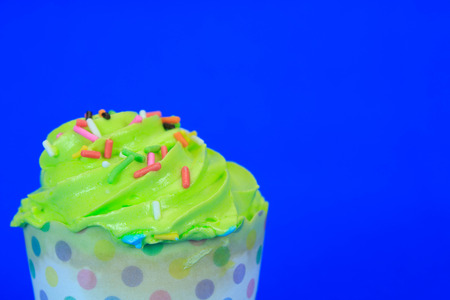 Green Cupcake with colorful candy on blue backgroundの写真素材