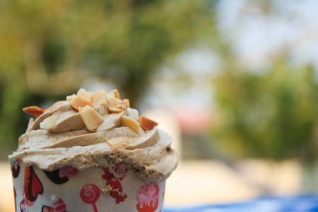 Coffee Cupcake with creamy with Almonds on blue picnic tablecloth in garden.の写真素材