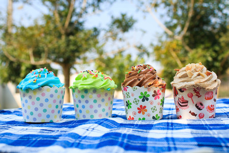 colorful cupcakes with colorful candy on blue picnic tablecloth in garden.の写真素材