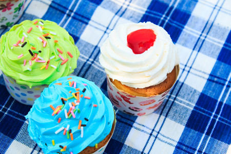 colorful cupcakes with colorful candy on blue picnic tablecloth in garden.の写真素材