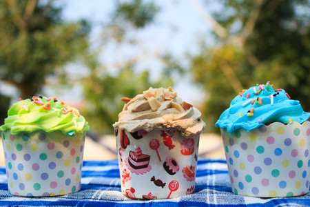 colorful cupcakes with colorful candy on blue picnic tablecloth in garden.の写真素材