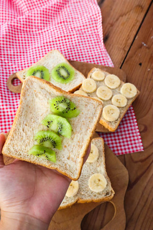 A Women's Hand Holding Wholegrain bread slices with kiwi.の写真素材