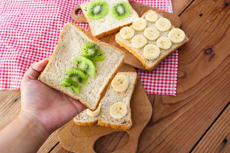 A Women's Hand Holding Wholegrain bread slices with kiwi.の写真素材