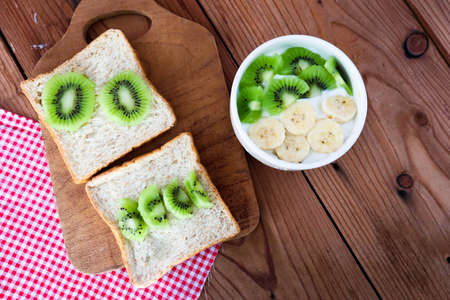Tropical fruit kiwi, banana bowl with yogurt and Wholegrain bread slices with kiwi.の写真素材
