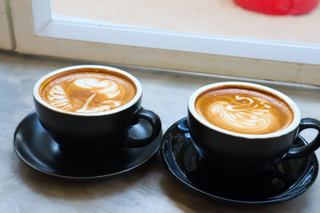 Coffee cup with latte art foam on table in cafe.の写真素材