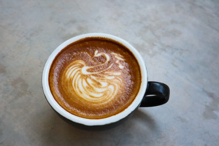 Coffee cup with latte art foam on table in cafe.の写真素材