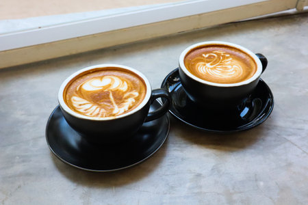 Coffee cup with latte art foam on table in cafe.の写真素材