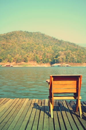 Wooden chair  on dock overlooking lake at Mae Ngad Dam and Reservoir, Chiang Mai, Thailandの写真素材