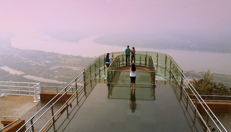 Nong Khai province, Thailand- April 28,2016: Tourists walking and taking photograph on transparent  sky walk to see view of Mekong River during sunset at Wat Pha Tak Suea, Sangkhom district,  Nong Khai province, Thailand.のeditorial素材