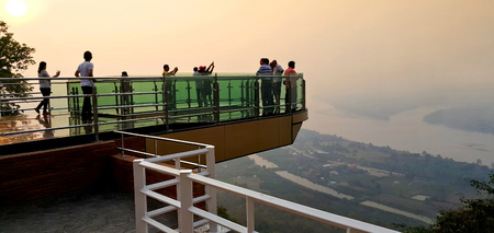 Nong Khai province, Thailand- April 28,2016: Tourists walking and taking photograph on transparent  sky walk to see view of Mekong River during sunset at Wat Pha Tak Suea, Sangkhom district,  Nong Khai province, Thailand.のeditorial素材