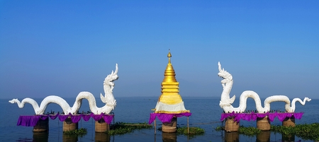 Phayao province, Thailand- April 20,2015: Couple of white serpent king or king of naga statues with golen stupa at Kwan phayao, Thailandのeditorial素材