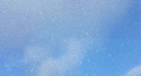 Water drops on glass with blurred blue sky backgroundの写真素材