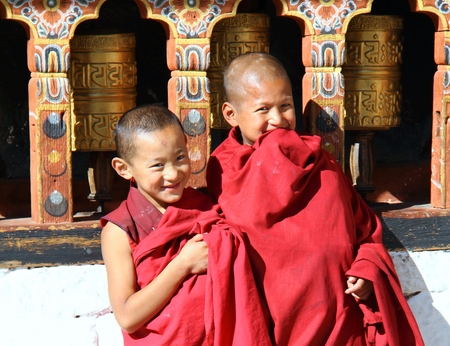 PARO, BHUTAN - NOVEMBER06,2012 : Unidentified smiling young monks standing by the religious prayer wheels at Paro Rinpung dzong, Paro, Bhutanのeditorial素材
