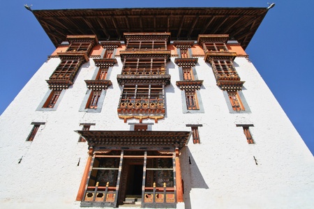 Traditional  Bhutanese style building decorated with carved wood window frames in Paro Rinpung Dzong, Buddhist monastery and fortress on a hill near the Paro Chu river. Paro, Bhutan.のeditorial素材