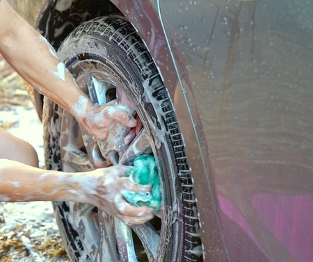 Hands of a man holding green microfiber cloth with soap cleaning  the car's wheelの写真素材