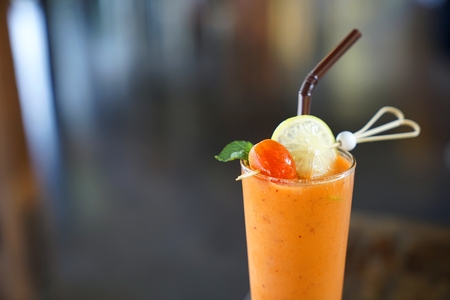 Fresh mixed tropical vegetable and fruit smoothie juice decorated with  fresh tomato and pice of limeの写真素材