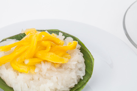 Thai traditional dessert (jackfruit with sticky rice) Wrapped in banana leaves on white paper backgroundの写真素材